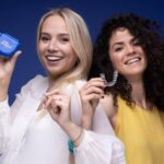 Na slici su dve osobe koje drže folije za ispravljanje zuba